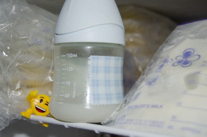 lot of frozzen breast milk in storage bags stored in the freezer and baby bottle with fresh expresed...