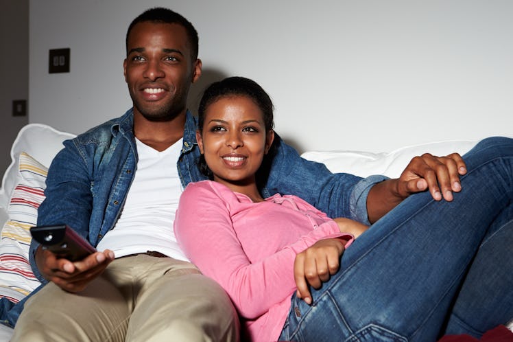 Couple Sitting On Sofa Watching TV Together