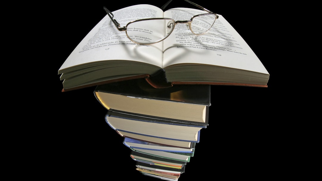 Book, pair of reading glasses, heart-shaped shadow, pile of books