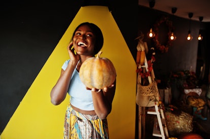 African american girl holding pumpkin against autumn mood decoration. Fall in Africa.