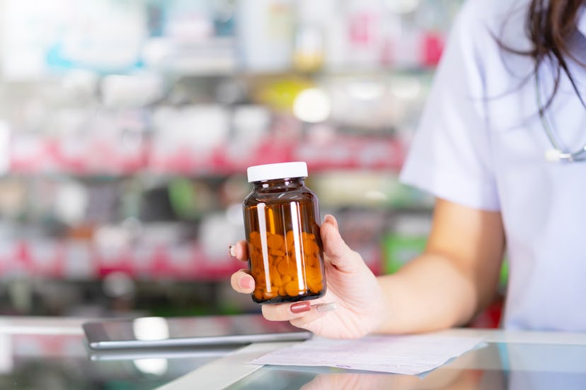The pharmacist holds a bottle of medicine in the pharmacy
