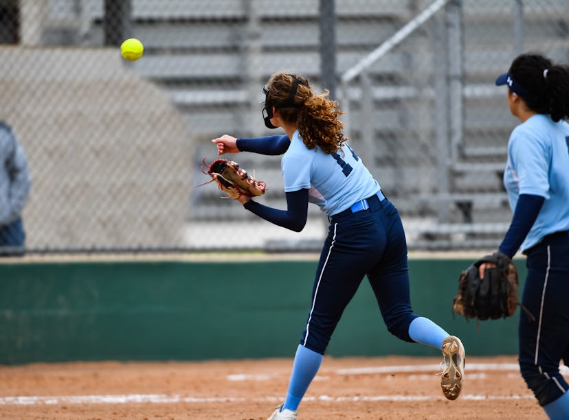 Softball player throwing the ball to first base for an out