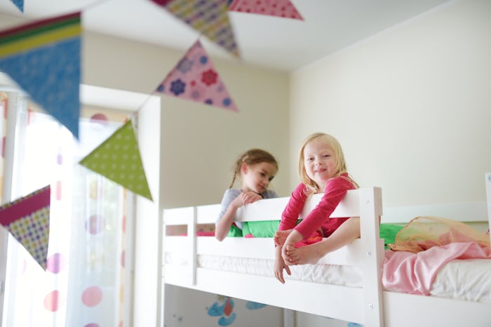 Two little sisters fooling around, playing and having fun in twin bunk bed on sunny sunday morning
