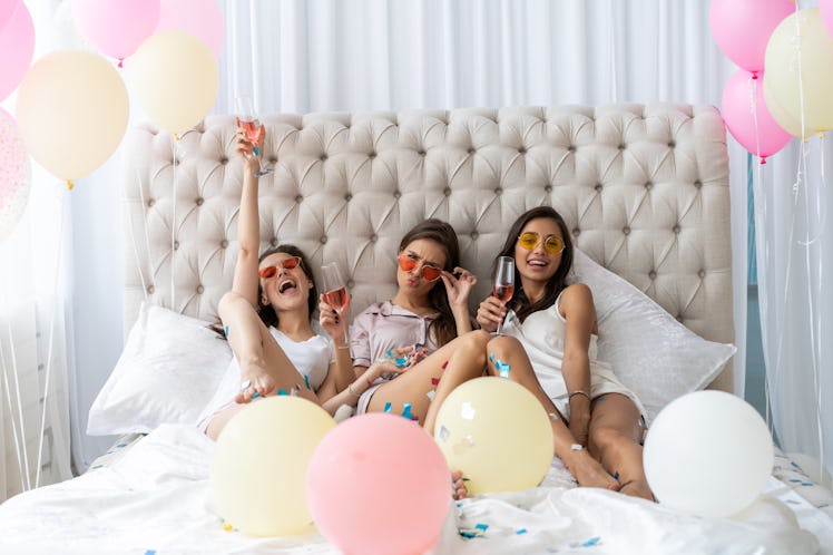 Pajama party. Attractive young smiling women in pajamas drinking champagne while having a slumber pa...