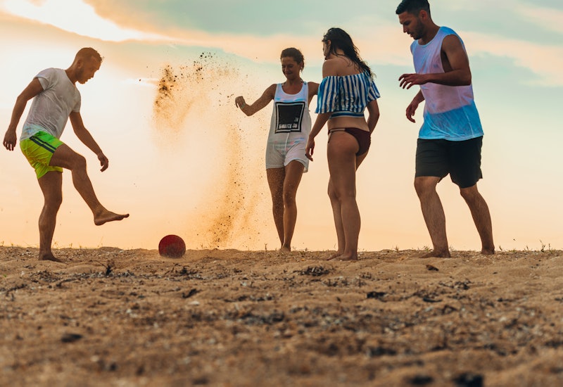 Concept of summer joy and multi ethnic friendship playing soccer