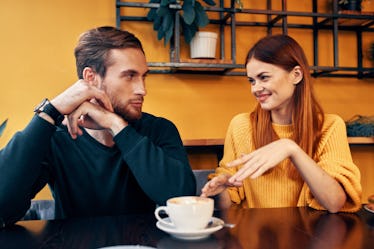 A woman in a yellow sweater man at a table in a cafe                          