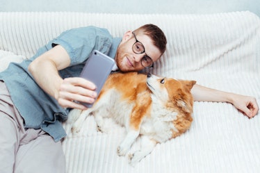 Young guy makes a selfie with a dog on his mobile. Concept blogging