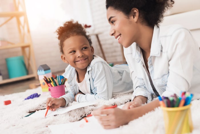 Mom and little girl lie on the floor with felt-tip pens. They draw on paper. They have fun together....