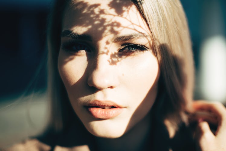 Closeup portrait of attractive blonde girl with shadows on the face.