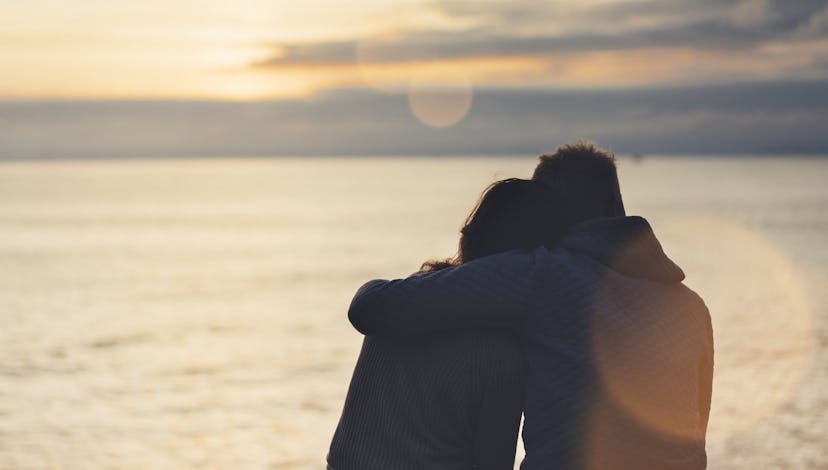 Couple hugging on the beach on background ocean sunrise, silhouette two romantic people cuddling and...