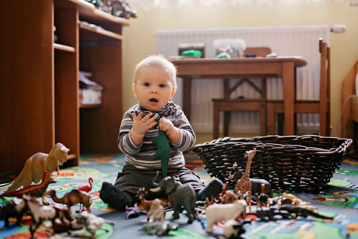 Beautiful little baby boy, toddler smiling at camera, animals and dinosaurs around him, indoor shot ...