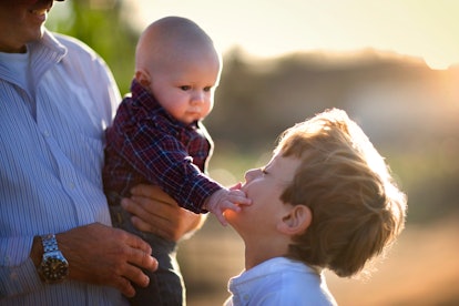 Young baby touching his older brother's face.