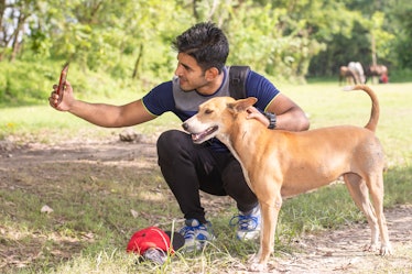 Young sports man taking selfie with dog in park, Animal lover sportsman concept.