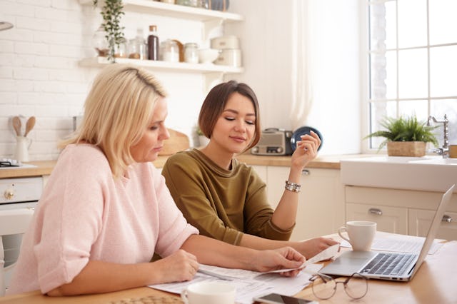A mom and daughter sit in the kitchen paying bills. According to a new poll, nearly half of American...