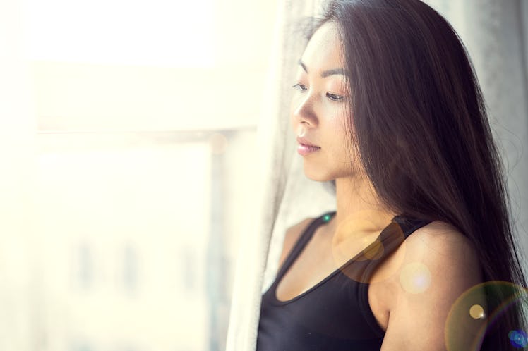 A young Korean girl looks out the window. Beautiful woman enjoys the morning. Wake up early in the m...