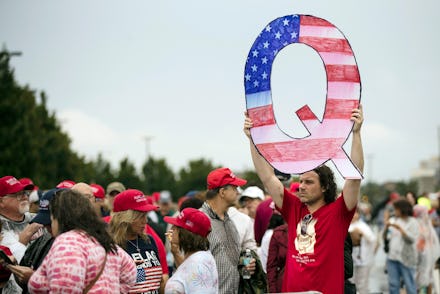 David Reinert holding a Q sign waits in line with others to enter a campaign rally with President Do...