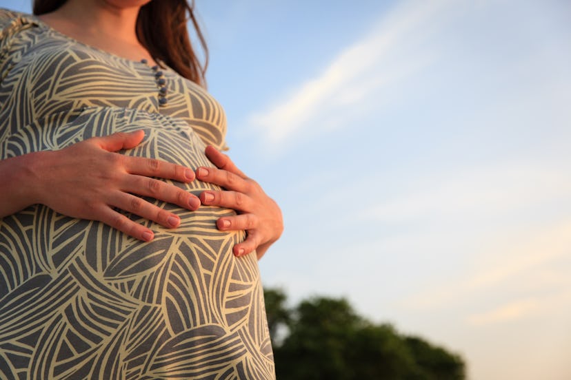 pregnant woman on sunset beach touching her belly with love