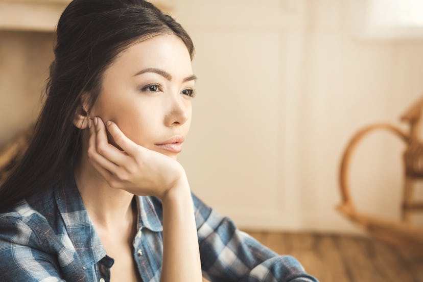 Portrait of young engrossed woman daydreaming with hand on chin