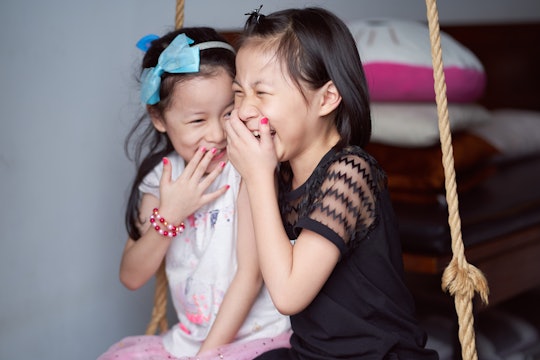 Asian sisters laughed happily sit on inhouse swing set