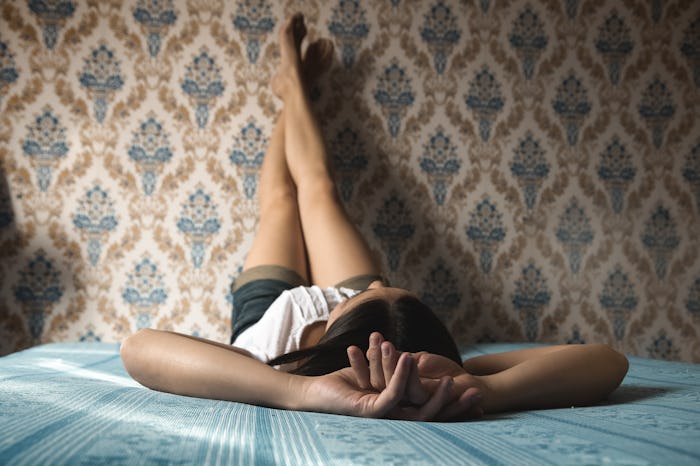 Woman lying in bed with her feet on the wall