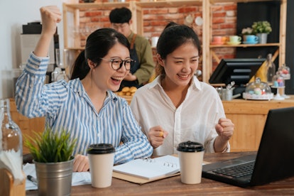 glad joyful positive freelance women coworkers looking at screen of laptop computer with raised hand...