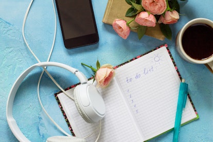 Make the list conceptual. Smartphone, headphones, coffee cup and notebook on a blue slate or concret...