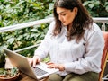 Portrait of beautiful plus size girl working on her laptop on balcony or terrace of cafe