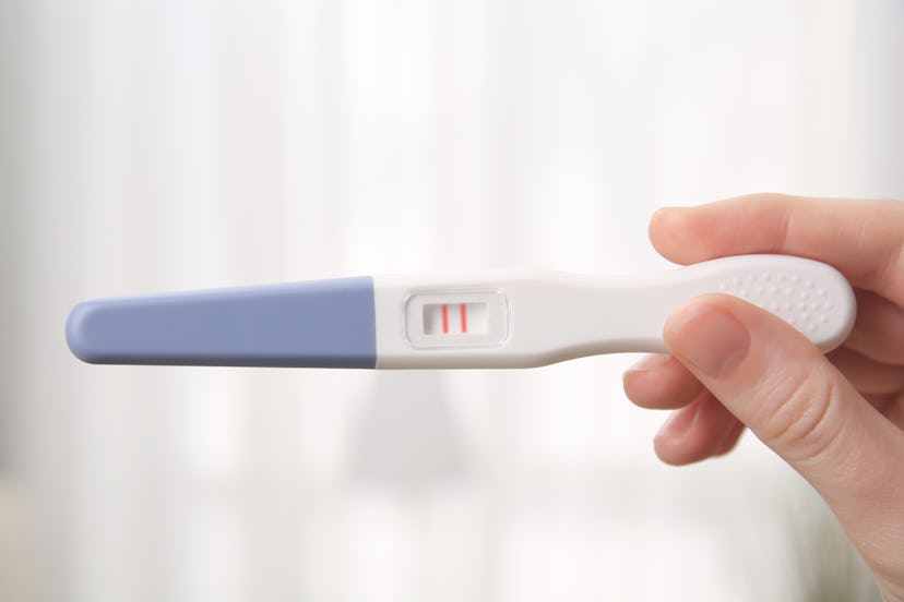 Pregnancy test in female hand on blurred background