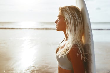 Surfer girl surfing looking at ocean beach sunset summer time