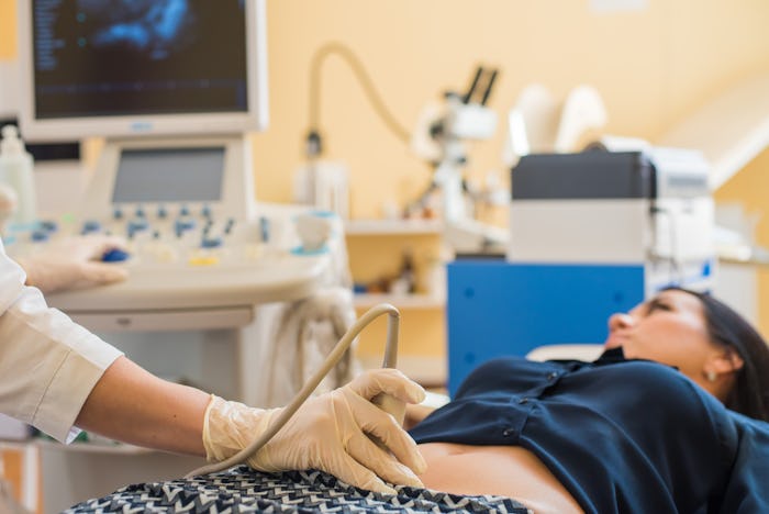 Happy pregnant female visiting women's doctor in the maternity center, doing ultrasound scan, worrie...