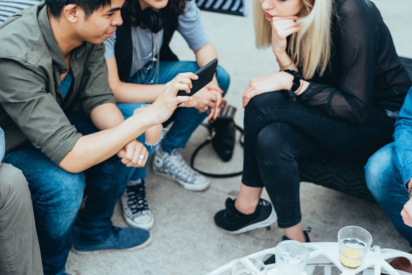 Group of friends millennials sitting outdoor bar using smart phone - technology, internet, happy hou...