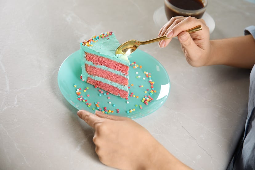 A person is about to take a bite out of a colorful birthday cake in a closeup picture. Athena says a...