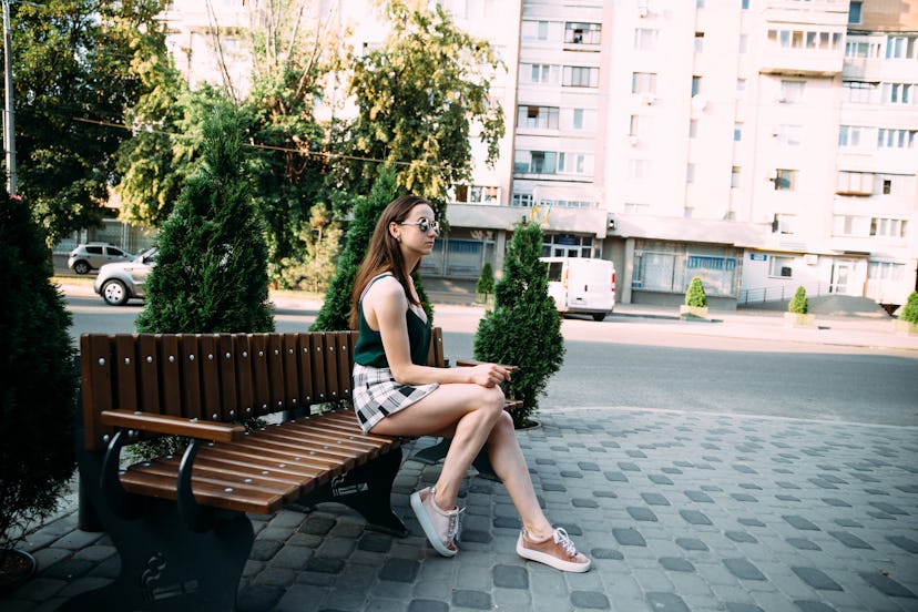 A girl in a black T-shirt and shorts in a park on a bench