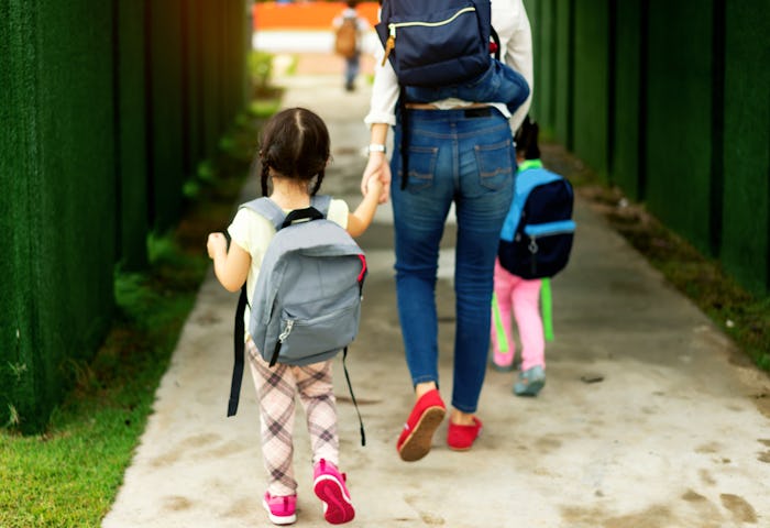 Mom and kids walking hand in hand into school