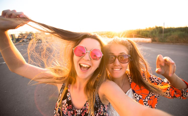 close-up lifestyle portrait of young best friends girls having fun at cool sunset.Travel concept,hap...