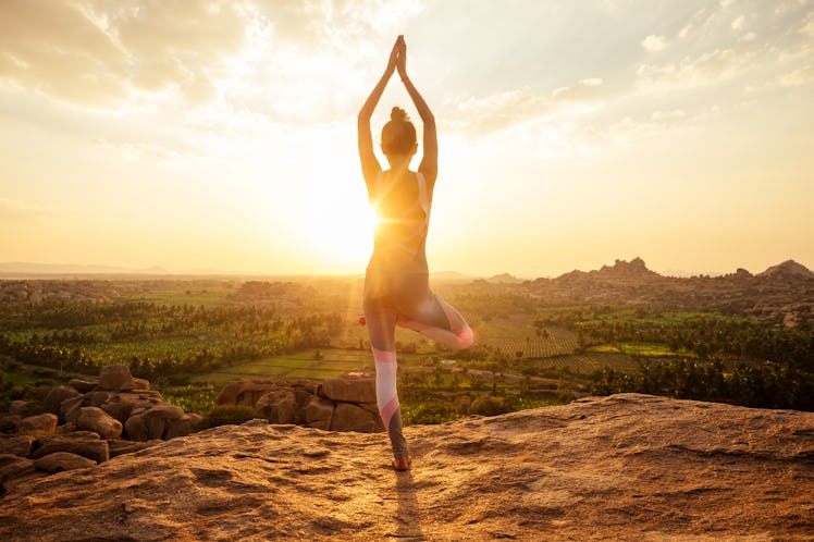 Yoga in Hampi temple copyspase at sunset.travel vacation copy spase lady with stylish jumpsuit