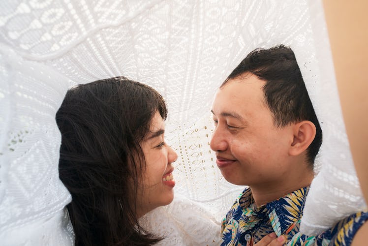 Young couple looking into each other's eyes. Romantic under lace fabric 
seaside.