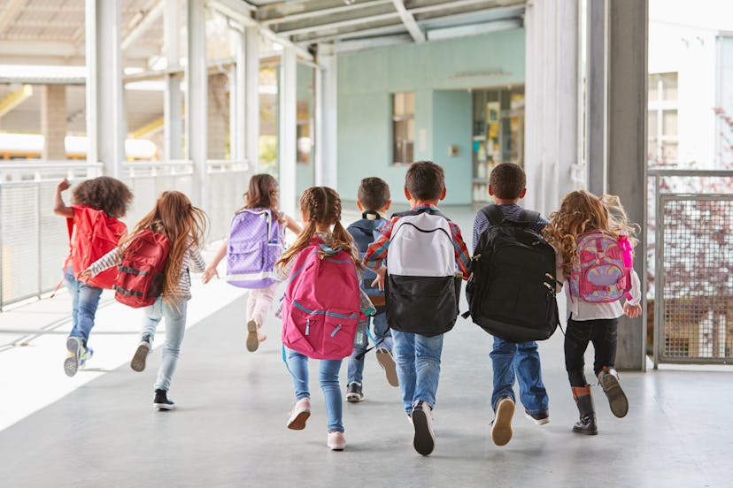 Elementary school kids run from camera in corridor, close up