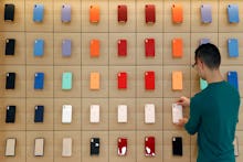 An Apple retail employee places a phone case on a display during a press preview of the new Apple St...