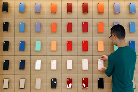 An Apple retail employee places a phone case on a display during a press preview of the new Apple St...