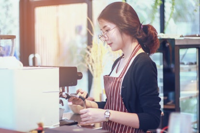 Women Barista smiling and using coffee machine in coffee shop counter - Working woman small business...
