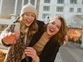 Two best friends laugh and take a picture while hanging out in the city in the fall.