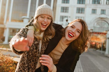 Two best friends laugh and take a picture while hanging out in the city in the fall.