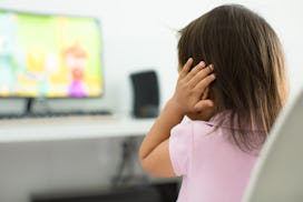 A terrified child, afraid of the loud sounds from the television. Autism.