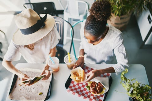 Two friends are eating a meal together at a restaurant. Comfort foods can be soothing to people livi...
