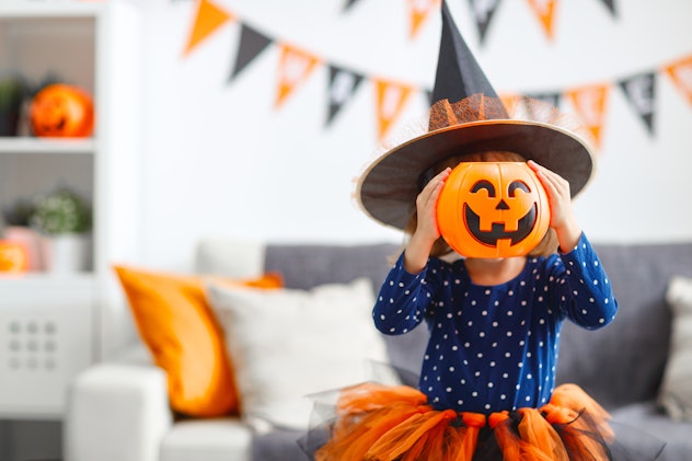 happy laughing child girl in witch costume to halloween