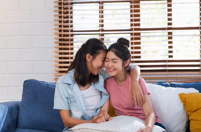 Happy asian lesbian couple hug each other with love on sofa at living room at home,LGBTQ lifestyle c...