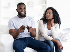 Boring date. Excited black guy rejoice winning in video game, annoyed tired and bored woman looking ...