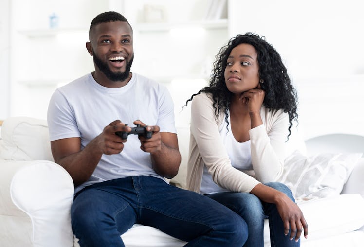 Boring date. Excited black guy rejoice winning in video game, annoyed tired and bored woman looking ...