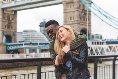 Happy multiracial couple in love in London. Black man and white woman embracing and laughing, bondin...